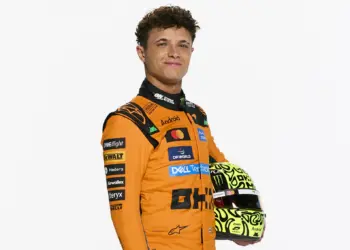 Lando Norris 2026 stúdiófotó, overálaban, sisakkal a kezében