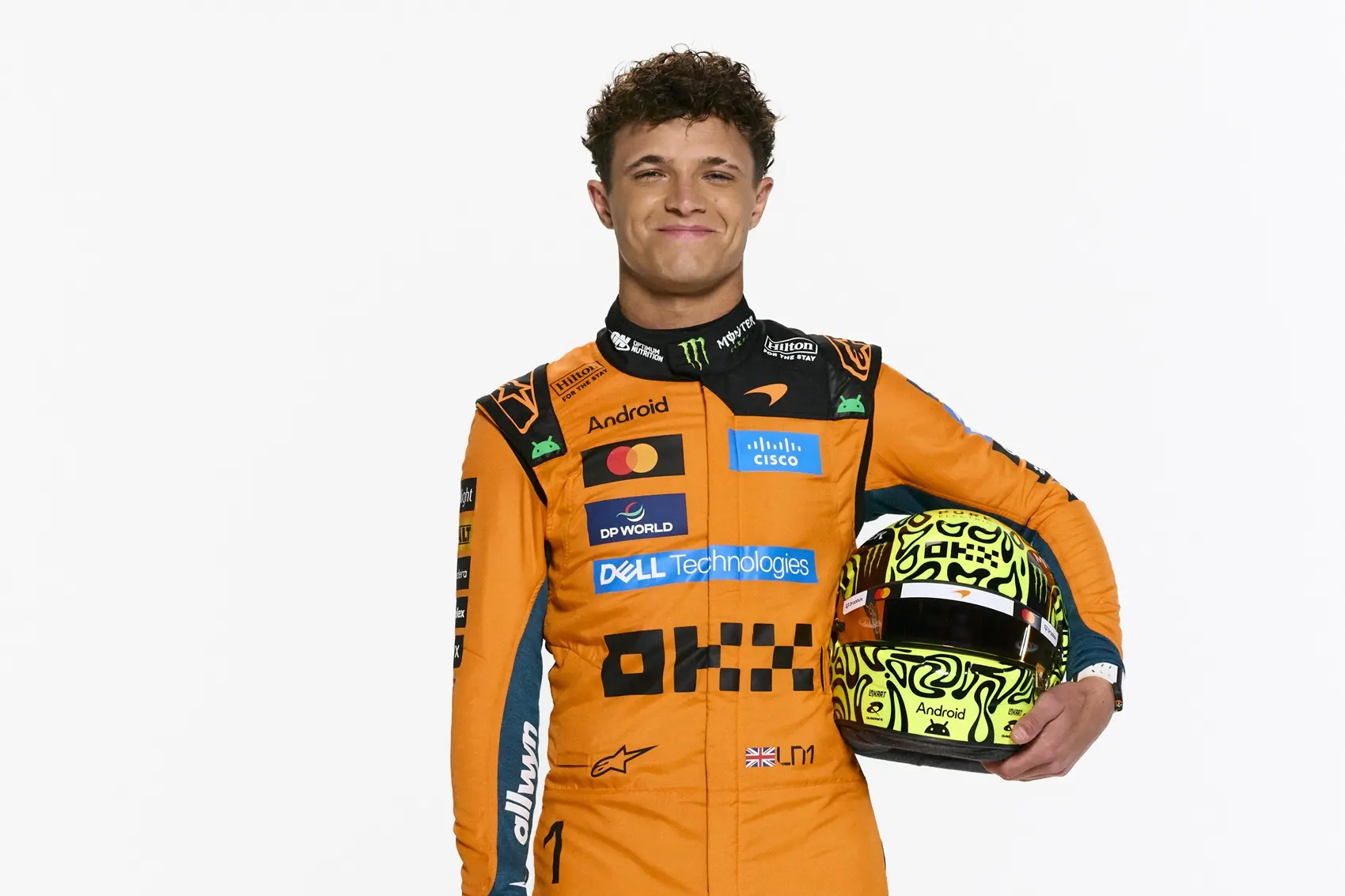 Lando Norris 2026 stúdiófotó, overálaban, sisakkal a kezében